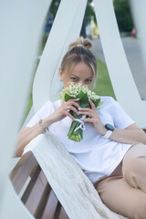 A young, beautiful girl with a bouquet of lilies of the valley on a walk.
