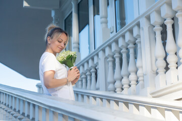 A young, beautiful girl with a bouquet of lilies of the valley on a walk.