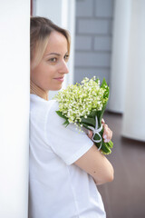 A young, beautiful girl with a bouquet of lilies of the valley on a walk.