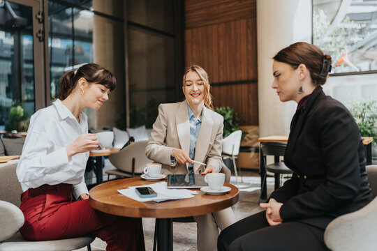 Three women discussing ideas while enjoying coffee together in an elegant cafe.