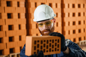 Production line of ceramics factory. Man worker holding clipboard and checking quality of bricks