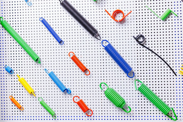 Colorful assortment of springs on perforated metal background