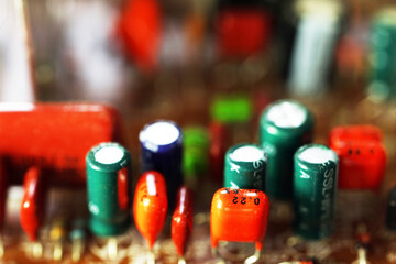 Close-up of electronic components on a circuit board. Various capacitors and resistors in different colors and sizes are visible. Focus on technology and electronics.