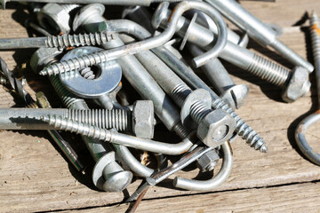 A collection of various metal fasteners including bolts, screws, and nuts arranged on a wooden...