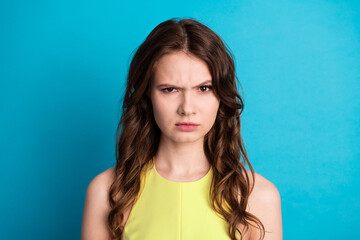 Portrait of a young woman in a yellow dress expressing discontent and frustration against a vibrant...