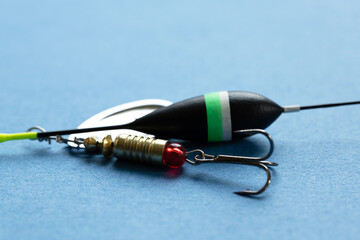 Fishing tackle including a black float with green stripe, a shiny lure, and a hook on a blue...