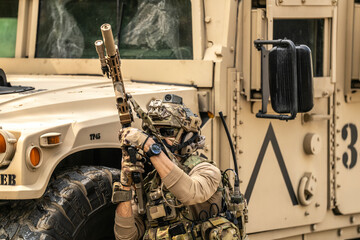Elite Special Forces Soldier Aiming Rifle Behind Armored Vehicle – Tactical Combat Gear, Camouflage Uniform, Modern Military Operation and Urban Warfare Concept Under Intense Conditions