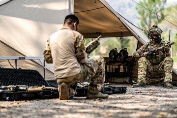 Special forces soldiers preparing tactical gear at military field base camp with weapons and...