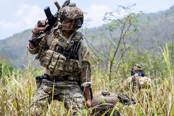 Special forces soldier holding rifle and communicating on radio during tactical operation in...