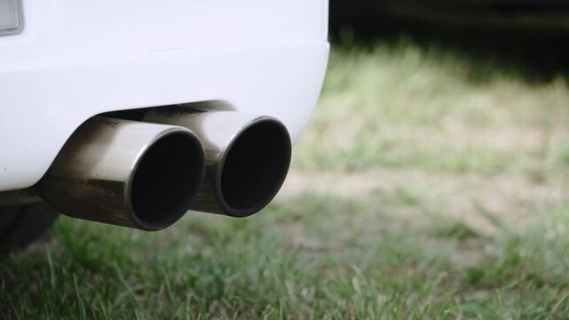 Double exhaust pipe of white sports car close up. Chrome plated heat resistant exhaust pipes of car with internal combustion engine and tuning of these elements.