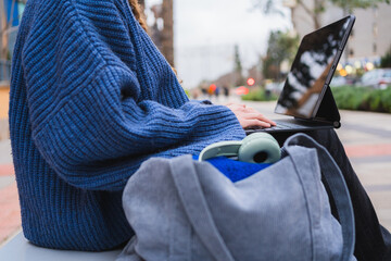 College student working on tablet in urban park, enjoying fresh air and technology