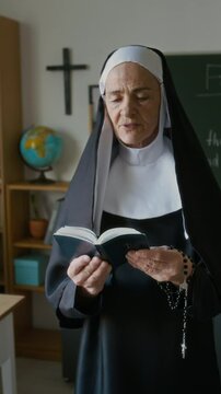 Vertical of focused elderly Caucasian nun in veil reading Bible out loud teaching Bible class in modern religious school