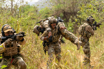 Fototapeta premium Soldier Carrying Injured Comrade During Tactical Combat Mission – Military Rescue Operation in Jungle, Armed Forces in Full Gear Providing Assistance Under Fire, Real Battlefield Scene