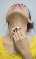 A female person is shown wiping, mopping, or rubbing clean using a cloth to clean the skin on the face and body.