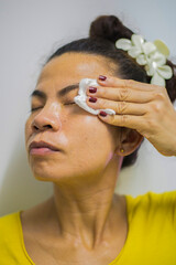 A female person is shown wiping, mopping, or rubbing clean using a cloth to clean the skin on the face and body.