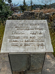 A close-up of a weathered marble memorial plaque written in Greek, commemorating Gakis Zeris, who was executed by Italian occupiers on March 19, 1943, during World War II. 