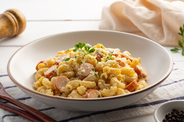 Creamy macaroni Pasta Carbonara sauce and hot dog sausage with parmesan cheese in white plate.