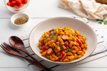 Stir Fried elbow Macaroni with hot dog sausage and fresh tomatoes in white plate.