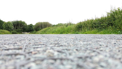 Blurred ground level perspective of sectioned gravel, green bushes and whitened sky.