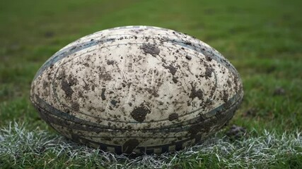 Gritty muddy rugby ball, in authentic game-day colors, representing a tough match on the field