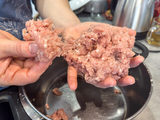 Female hands make meatballs with red fat mince, close up