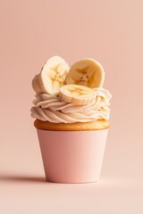 Cupcake with creamy frosting topped with fresh banana slices, set against a soft pink background. Perfect for bakery, sweet treats, and minimalist dessert visuals.