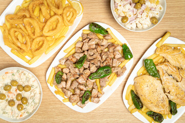Overhead view of various spanish dishes including chicken, squid, french fries, and salads, offering a diverse culinary experience