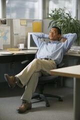 Relaxed young Black man enjoying a break in a bright office space.