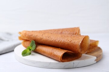 Delicious fruit leather rolls and mint on white table, closeup