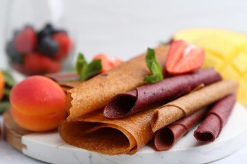 Delicious fruit leather rolls, mint, apricot and strawberry on table, closeup