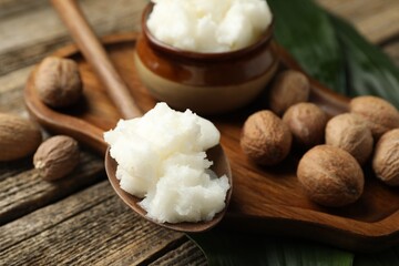 Natural shea butter, nuts and leaves on wooden table, closeup