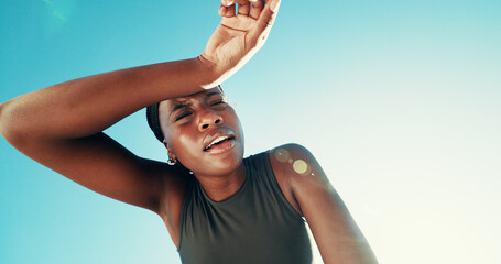 Fitness, tired and black woman wipe sweat for health, wellness or exhausted by blue sky. Runner, fatigue and space on break outdoor for intense exercise, breathing or rest for recovery with low angle