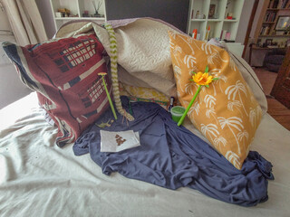 Messy bed with pillows and yellow flower