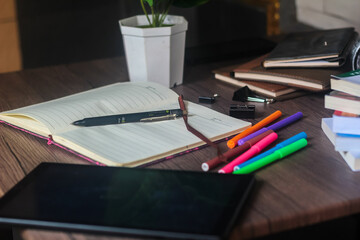 For educational purposes, several colored markers and notebooks are on the wooden table.