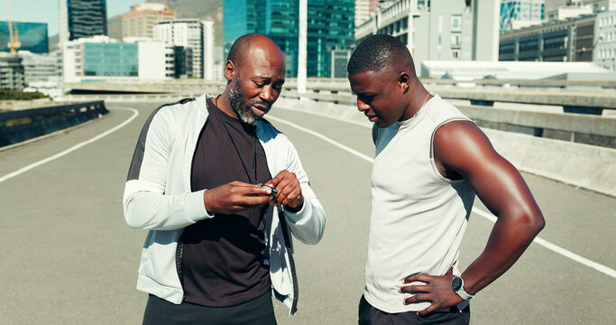 Fitness, athlete and personal trainer with stopwatch in city for running time, progress and speed. Bridge, black people and instructor with stats for performance, workout pace and monitor heart rate - Powered by Adobe