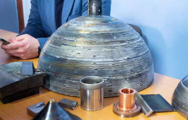 Objects printed on 3D printer from filament of molten metal on table. Object printed by 3D printer from metal. Additive manufacturing solution. Object created on 3D printer from melting metal thread