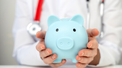 Doctor with stetascope and piggy bank in his hands. The Concept of Medicine