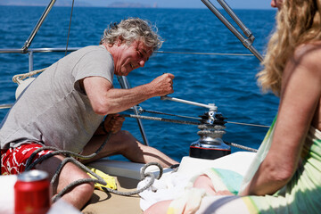 Senior couple maneuvering sailboat winch on Costa Brava, Spain