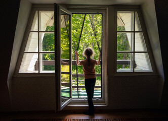 Magnetic mosquito net mesh on balcony door. Back view of child going outdoors to home balcony,  mesh preventing insects coming inside.