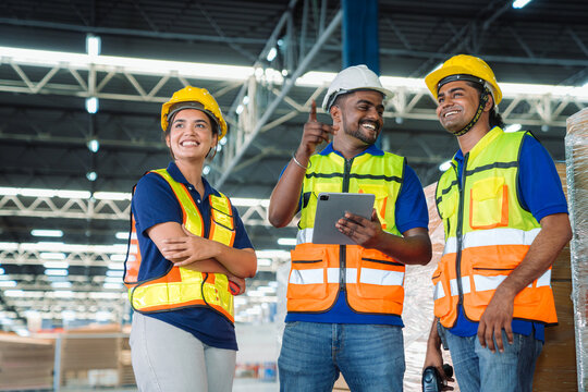 Diverse workfoce team black men,woman factory worker wear safety helmet, safety vest use tablet for industrial warehouse job.Teamwork efficient success modern logistic manufacture operation management