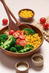 Broccoli, corn, quinoa, tomato salad in wooden bowl on light beige background. Healthy food concept