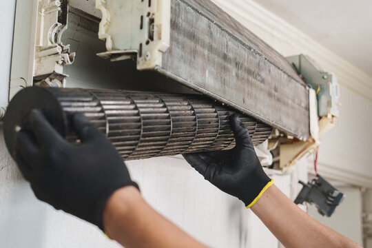 Technician Removing Blower Fan from Wall-Mounted Air Conditioner Unit