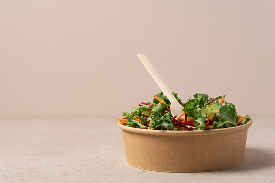Healthy salad with carrot and beetroot in craft bowl on beige background with copy space. Vegan, diet, food delivery concept