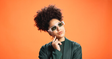 Sunglasses, thinking and woman in studio for fashion, reflection or solution on orange background....