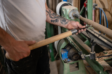 Carpenter using wood lathe to create wooden object in workshop