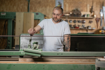 Carpenter using belt sander in workshop on woodworking project