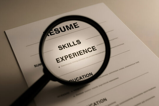 A magnifying glass focusing on the skills and experience section of a resume symbolizing job search and professional competence for career advancement - Powered by Adobe