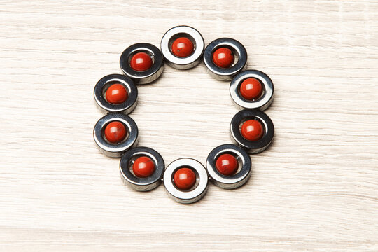 Pulseira de esferas de hematita com pedras de cor vermelhas no centro. 