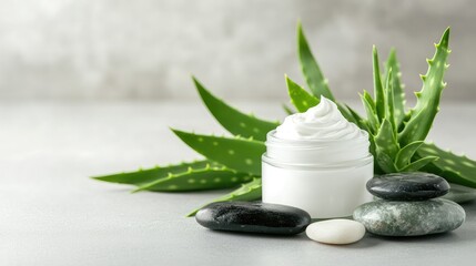 Glass jar of whipped body cream with aloe vera leaves and spa stones arranged beside