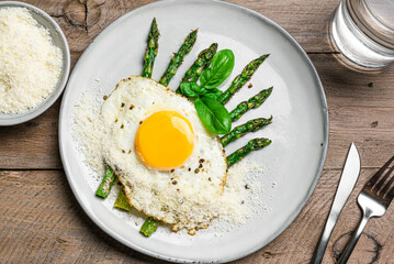 Fried egg with green asparagus and grated parmesan cheese for breakfast